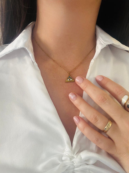 Necklace with a triangle pendant worn by a person in a white shirt.