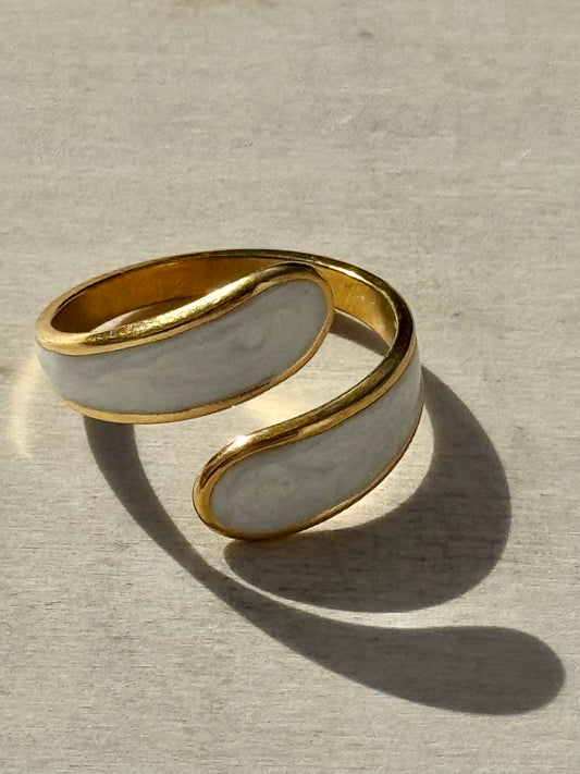 Gold and white ring on a textured beige surface