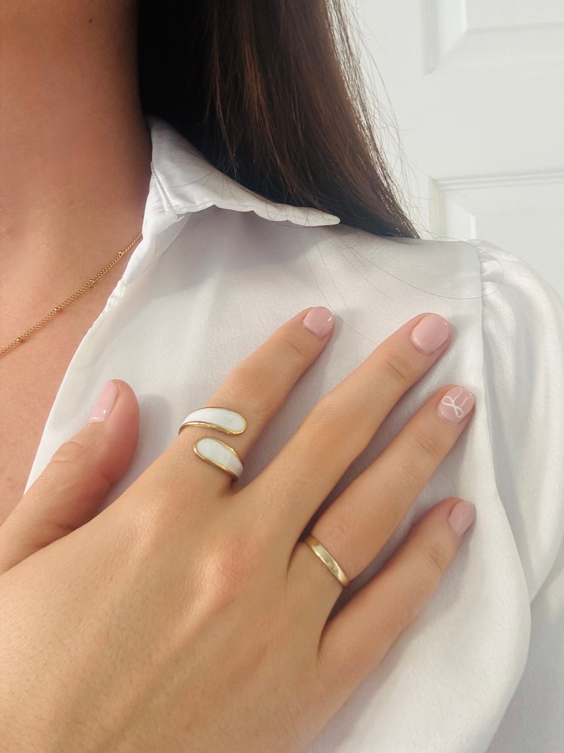 Close-up of a hand wearing two gold rings with a white shirt background