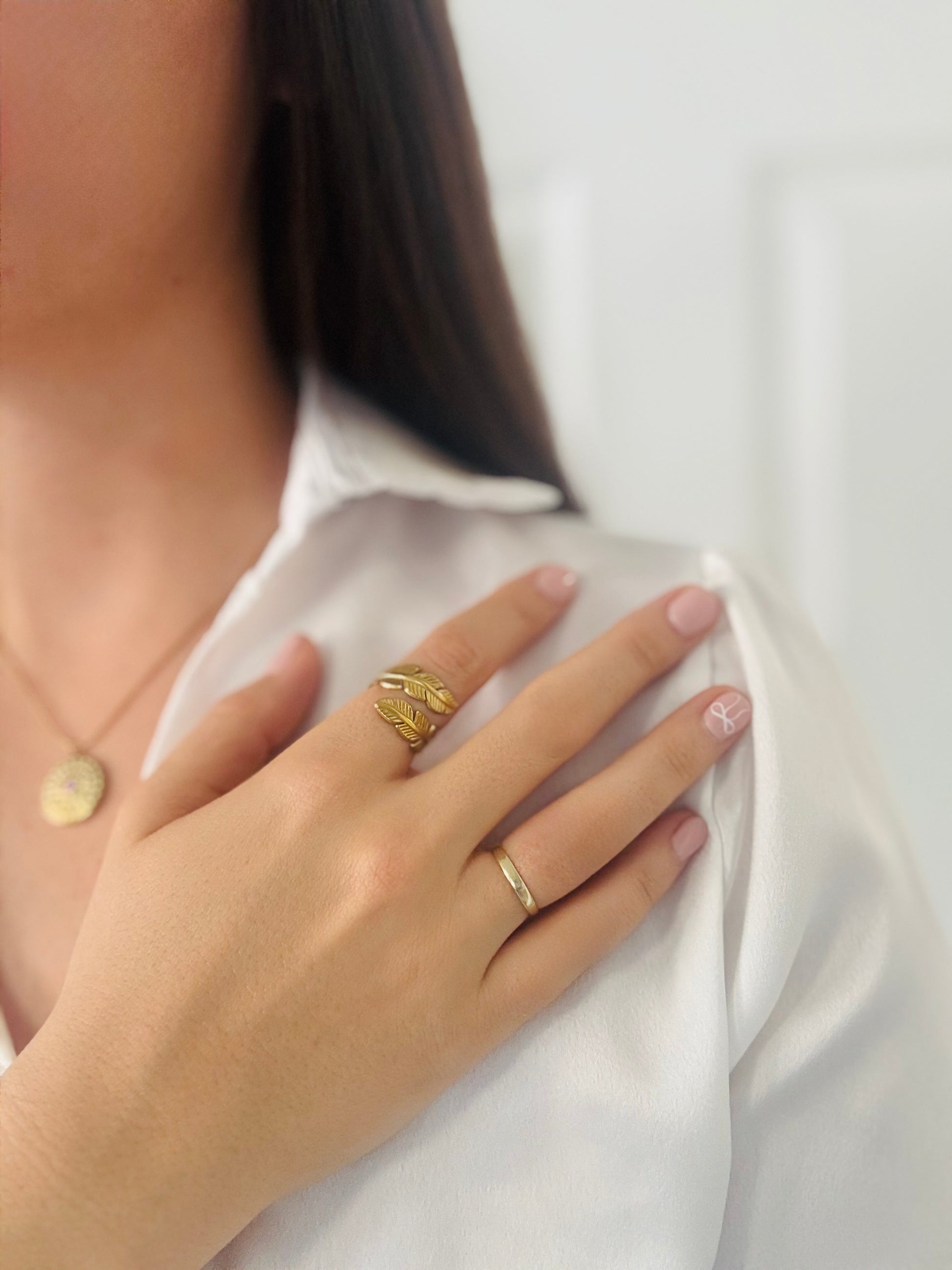 Close-up of a person wearing a gold ring on a white background