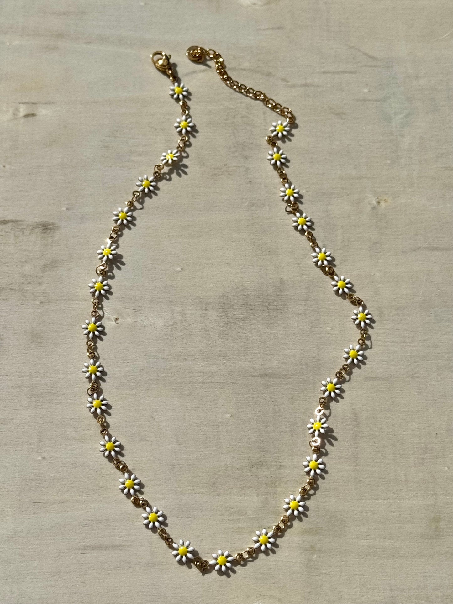 Necklace with daisy flower pendants on a textured surface