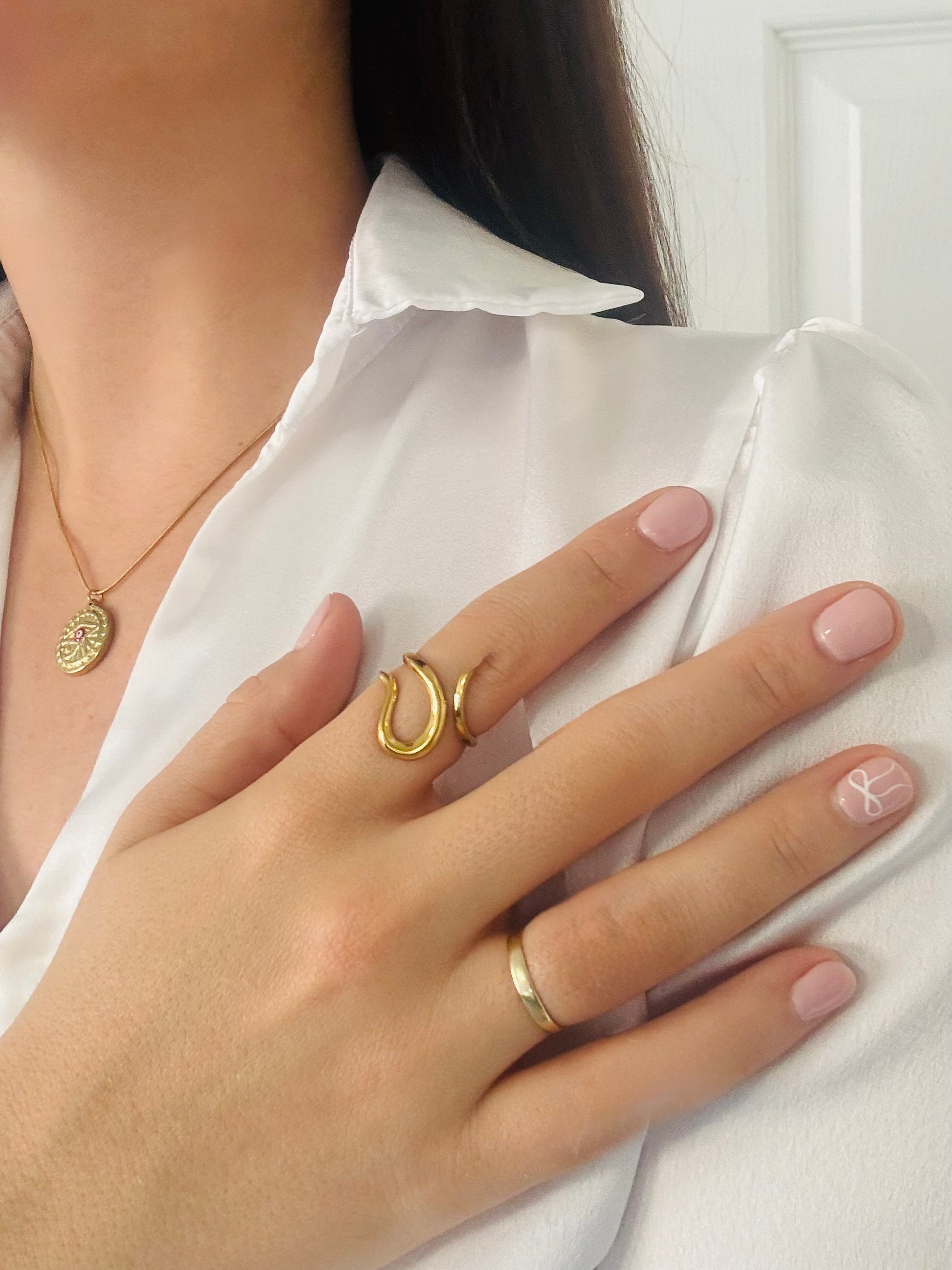Hand wearing a gold ring with a white shirt background