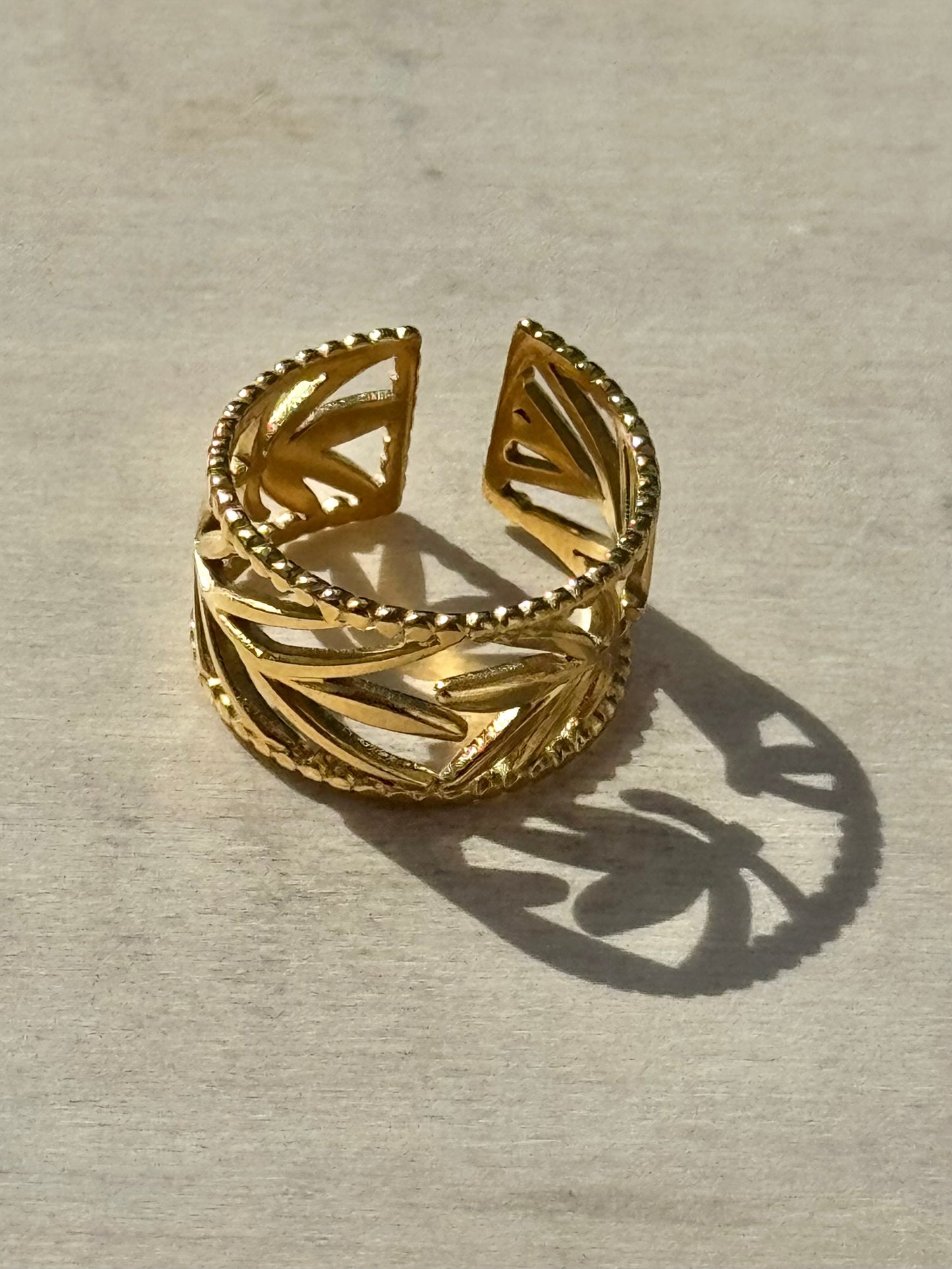 Gold openwork ring on a light wooden surface