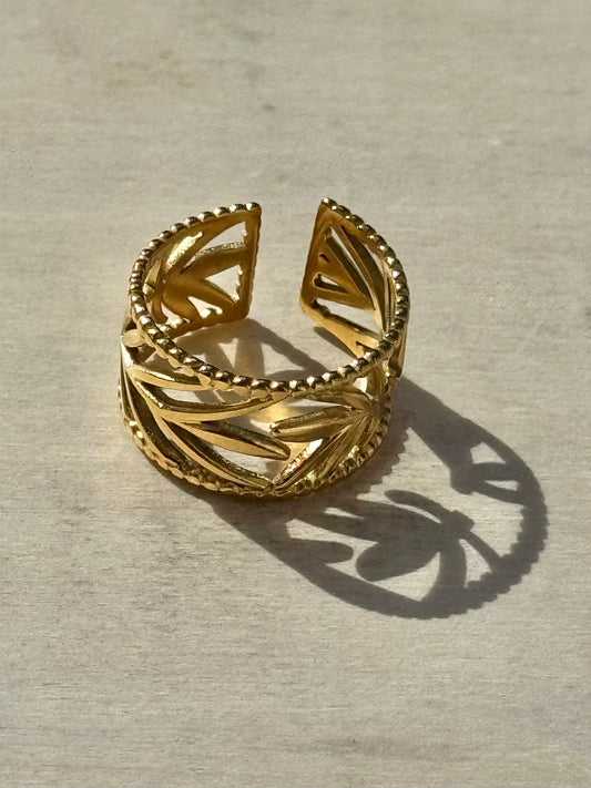 Gold openwork ring on a light wooden surface
