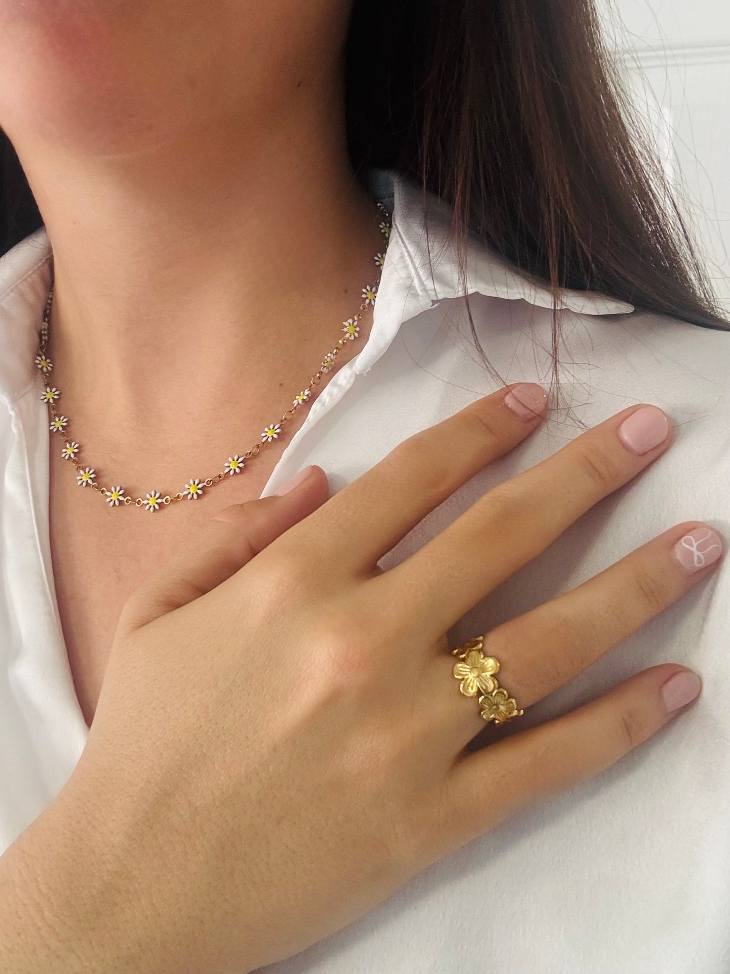 Gold floral necklace and ring on a white shirt