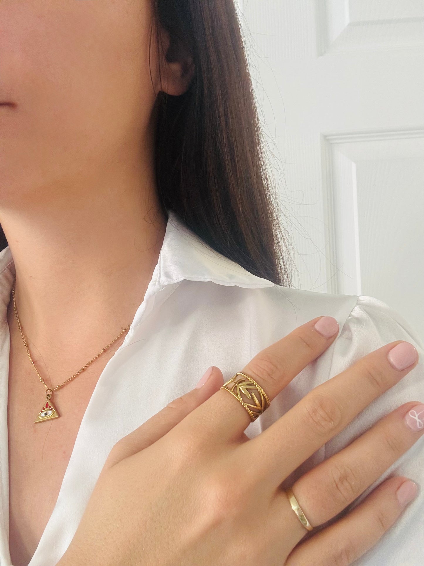Close-up of a person wearing gold jewelry including a necklace, ring, and bracelet.