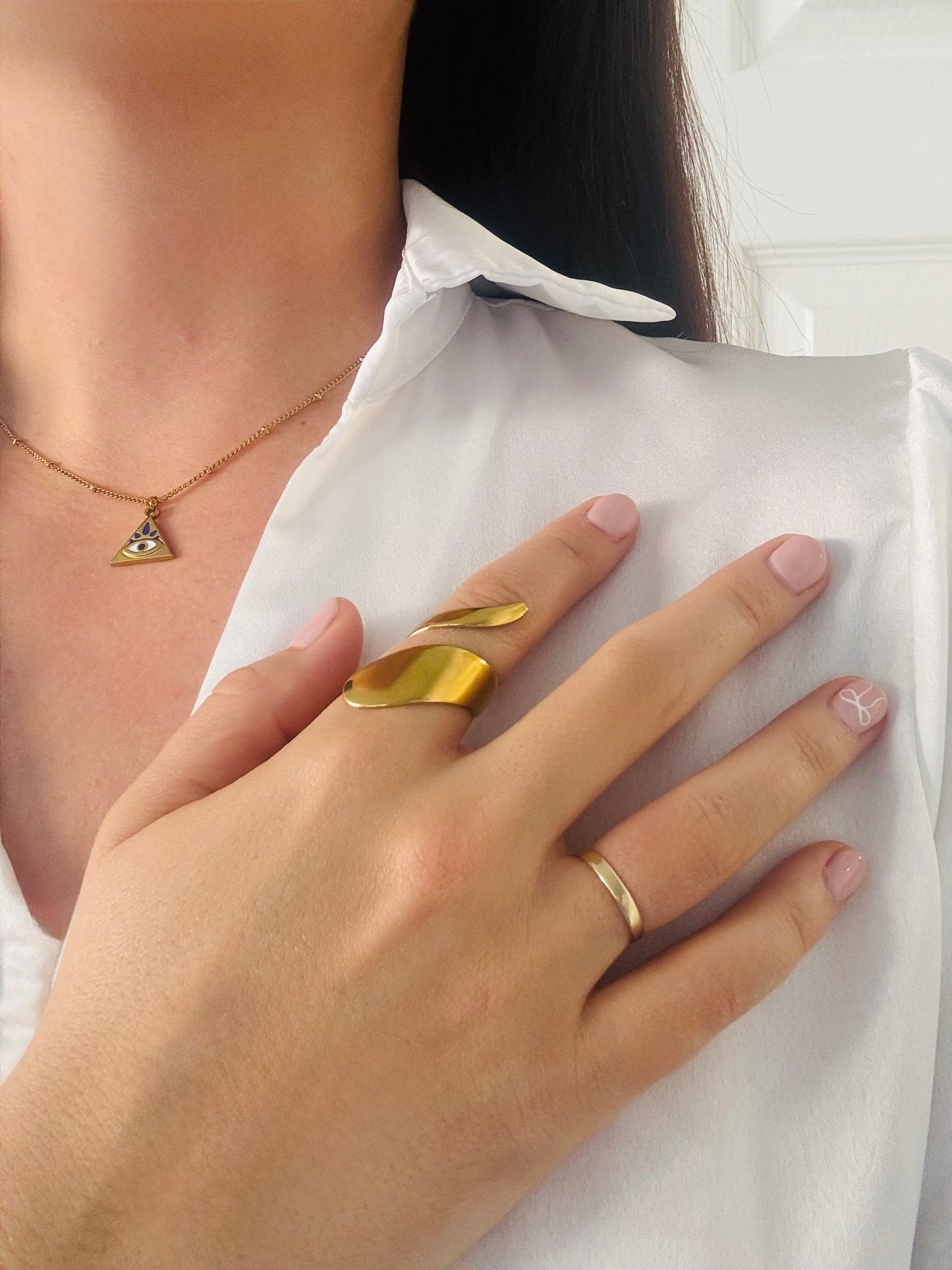Close-up of a person wearing gold jewelry on a white shirt background