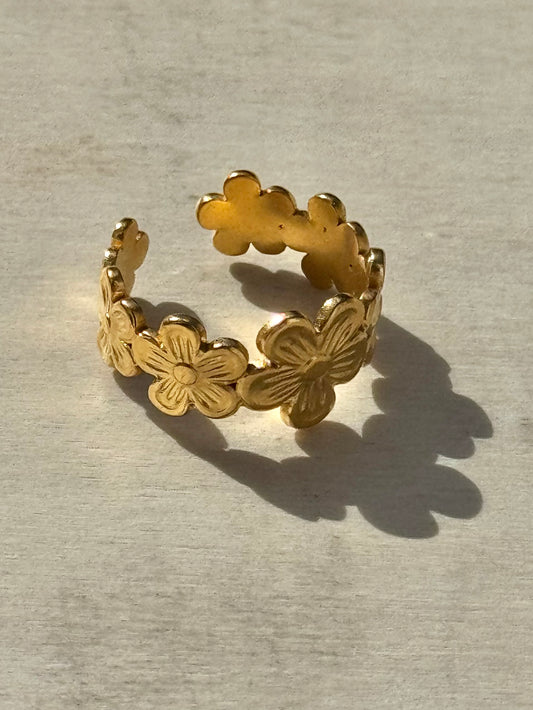Gold floral ring on a textured surface