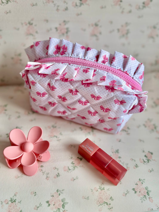 Floral-patterned pouch with a pink zipper, a pink flower-shaped object, and a red lipstick on a floral background.