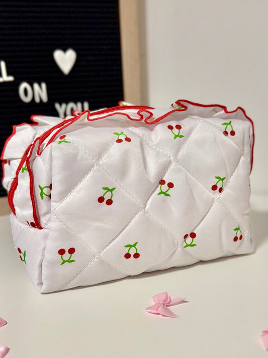 White quilted bag with red stitching and cherry designs on a light background