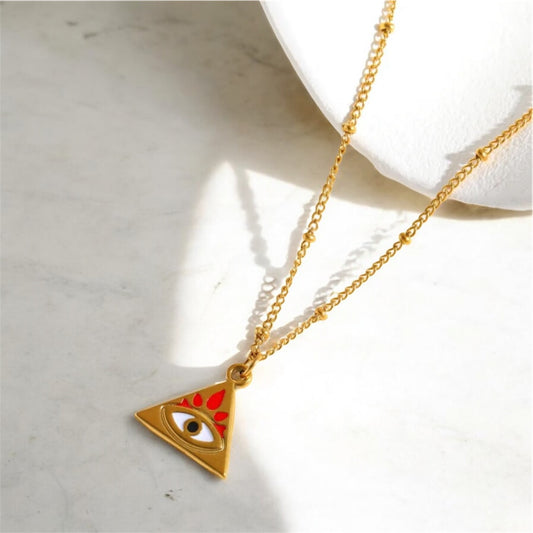 Gold necklace with a triangle pendant featuring an eye design on a light background